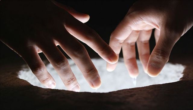 Hovering hands reaching over glowing mist-filled basin with luminous fingers, dark ambience