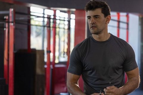 Focused athlete training at gym with pull-up rig and resistance cord