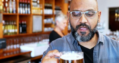Asian Man Tasting Beer in Cozy Bar - Download Free Stock Images Pikwizard.com