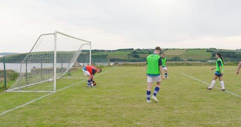 Soccer Players Practicing on Scenic Field with Goalkeeper