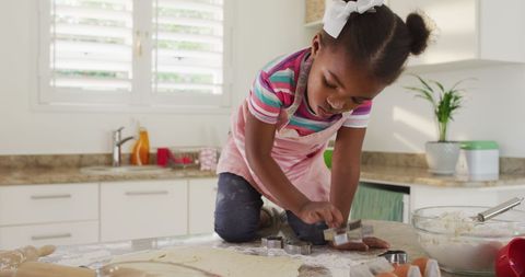Happy African American Girl Cutting Cookies in Bright Kitchen