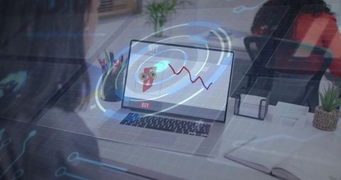Displaying laptop with NFT owl and rising red chart on office desk, coworkers collaborating