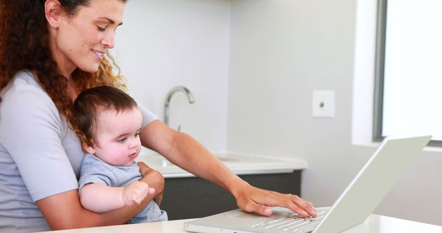 Mother Working from Home with Baby on Lap in Kitchen - Download Free Stock Images Pikwizard.com