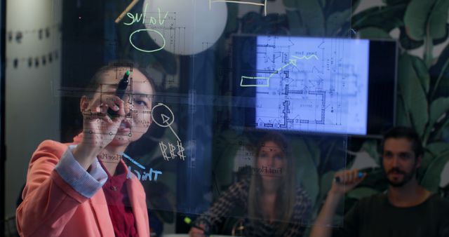 Architect drawing building plans on a glass board while colleagues observe. Perfect for using in contexts related to architecture, presentations, teamwork, and collaboration. Ideal for illustrating innovative approaches in design, office work settings, and professional discussions.