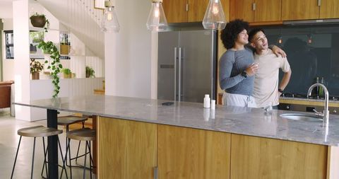 Multiracial Couple Enjoying Time Together At Modern Kitchen Island