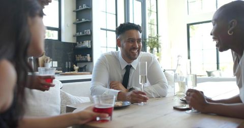 Smiling man holding champagne at modern kitchen table during friendly home toast