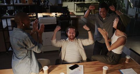 Diverse Team Celebrating Success at Night in Modern Office