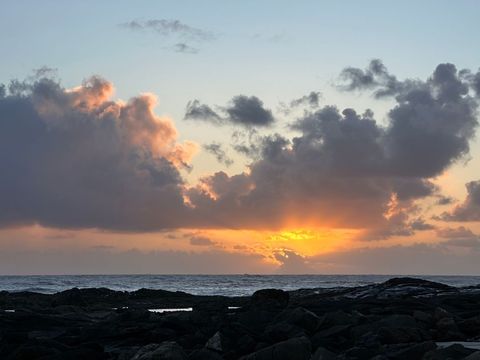 Dramatic beach sunrise over rocky coastline