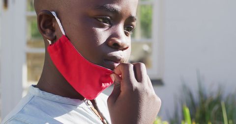 Boy Adjusting Face Mask Outdoors on Sunny Day