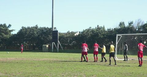 Athletes Preparing for Free Kick on Grass Field at Soccer Match