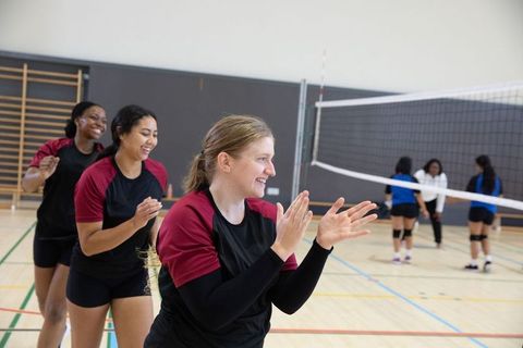 Female volleyball team clapping and celebrating after point on indoor court