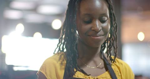 African american barista smiling and making coffee in warm cafe light, closeup portrait