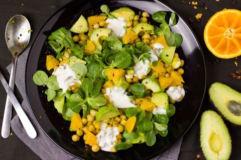 Serving Vibrant Chickpea Avocado Orange Salad Featuring Baby Greens and Yogurt Drizzle