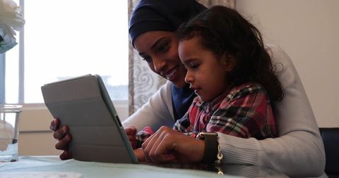 Mother and daughter bonding through tablet use at home