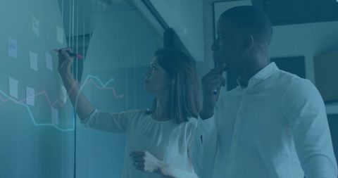 Business professionals analyzing data on office glass wall