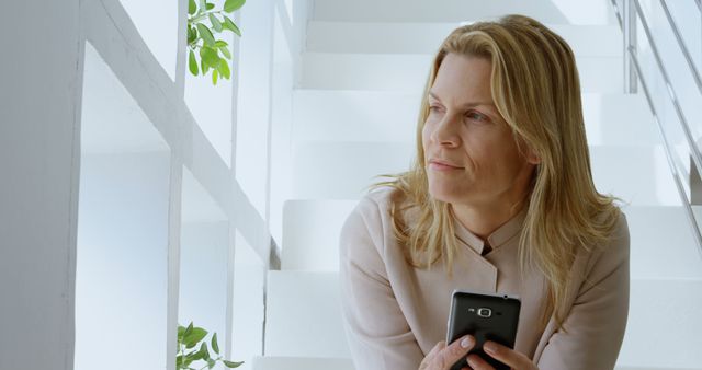 Thoughtful Businesswoman Holding Smartphone in Modern Office - Download Free Stock Images Pikwizard.com