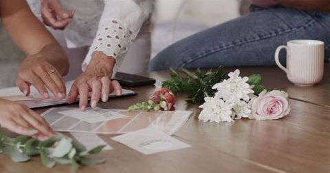 Women discussing wedding plans with floral arrangements and invitations
