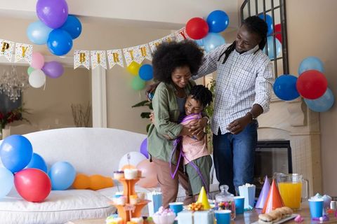 African american family celebrating child's birthday at home, parents hugging child