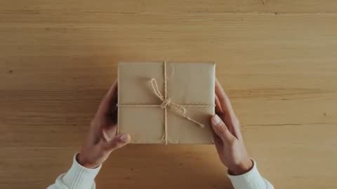 Hands Carefully Unwrapping Brown Craft Paper Box