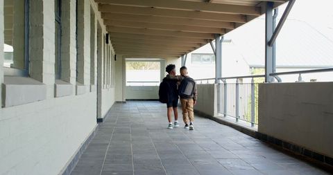 Teenage friendship: boys walking arm-in-arm down school corridor
