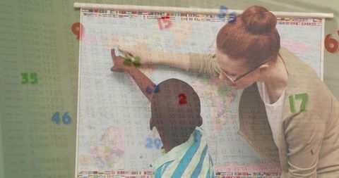 Teacher guiding student over world map in classroom pointing at countries for geography lesson
