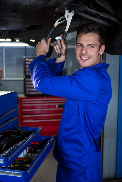 Portrait of happy mechanic servicing a car at repair garage