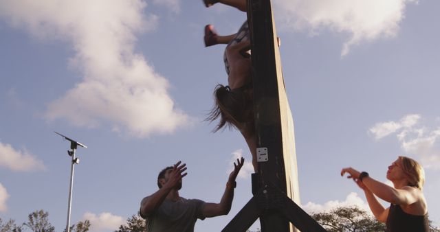 Group of people engaging in challenging obstacle course outdoors. Demonstrates teamwork and physical endurance. Useful for themes like fitness, outdoor activities, teamwork, motivation, and goal achievement promotions. Ideal for advertising fitness programs and team-building events.