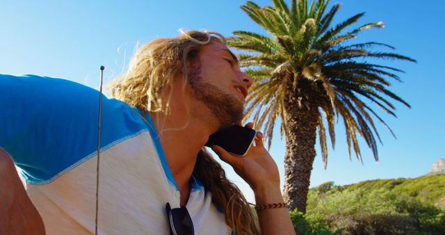 Young Man Talking on Phone Outdoors Near Palm Tree on a Sunny Day - Download Free Stock Images Pikwizard.com