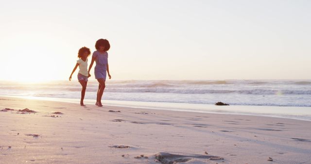 African american mother and daughter having fun walking together on the beach. family travel vacation leisure concept