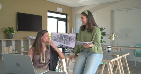 Diverse female team collaborating on 3D architectural plan in bright modern coworking space