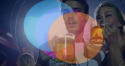 Young friends holding beer mugs enjoying lively nightclub party with colorful lights