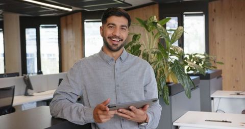 Smiling professional holding tablet in modern office environment