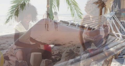 Family beach day with child building sandcastle by hammock