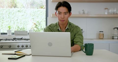 Man Concentrating with Laptop at Cozy Kitchen Workspace