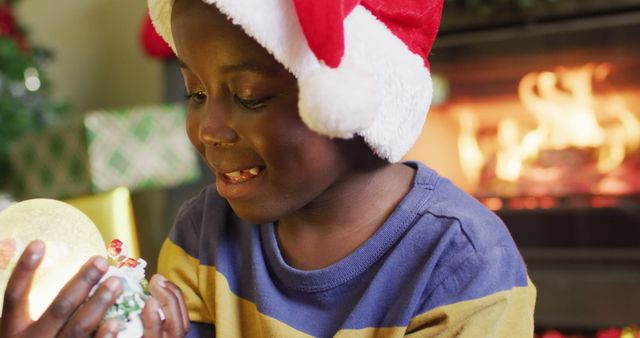Happy african american boy playing with snow globe. Spending quality time with family at christmas concept.