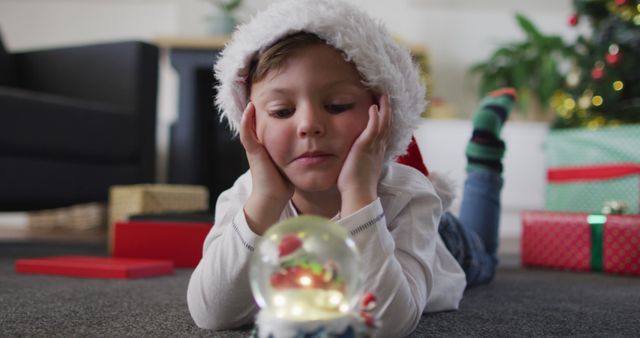 Child Wearing Santa Hat Admiring Christmas Snow Globe - Download Free Stock Images Pikwizard.com