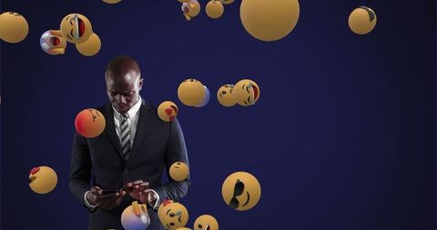 Businessman engaged on smartphone with floating emojis around