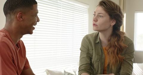Interracial couple having calm honest conversation in bright minimalist bedroom
