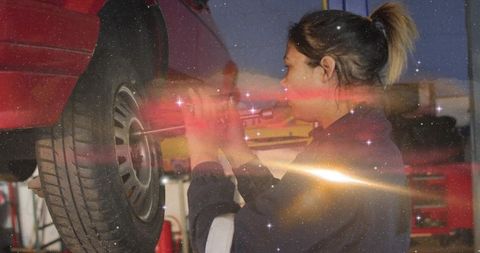 Female Mechanic Tightening Wheel with Breaker Bar on Lift in Auto Repair Garage