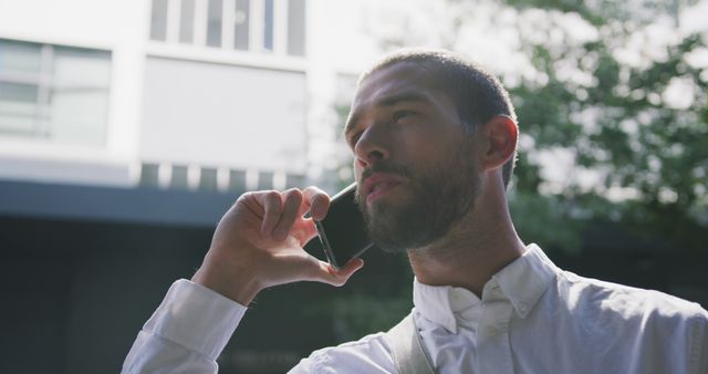 Confident Man in White Shirt Talking on Smartphone Outdoors - Download Free Stock Images Pikwizard.com