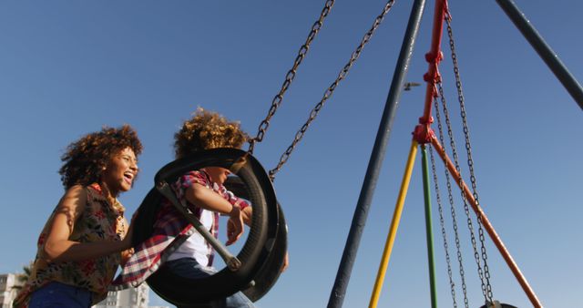 Mother and child enjoying a playful swing ride in a park, both laughing and having fun. Suitable for use in family wellness articles, parenting blogs, lifestyle advertisements, and children's outdoor activity promotions.