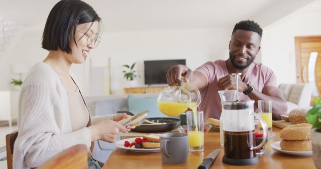 Happy diverse couple sitting at table and having breakfast. Spending quality time at home concept.