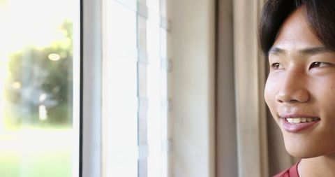 Joyful Asian Teen Boy Smiling at Home by the Window