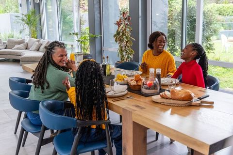 African american family laughing and sharing bread around bright wooden dining table