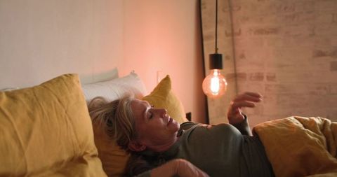 Senior woman relaxing in cozy bedroom with warm lighting