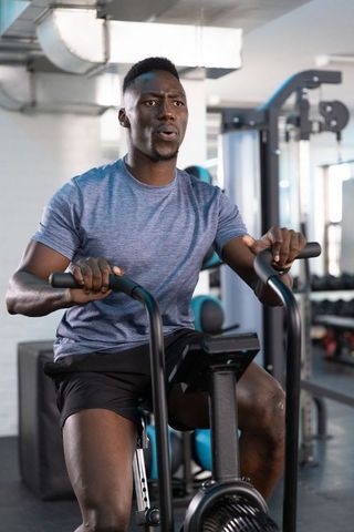 Young man pedaling on air bike in gym showing determination and intense cardio workout