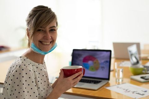 Smiling Businesswoman in Office Holding Coffee Mug with Laptop Chart