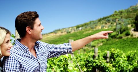 Joyful Couple Exploring Scenic Vineyard on Clear Day