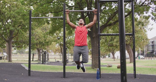 This image shows a man doing pull-ups in an outdoor gym, highlighting fitness and strength training. Ideal for articles or promotions about outdoor workouts, healthy lifestyles, and exercise routines. Can be used in fitness blogs, gym advertisements, and motivational posters.