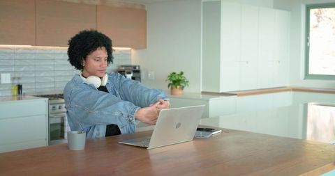 Mid adult stretching at modern kitchen island with laptop during remote work break